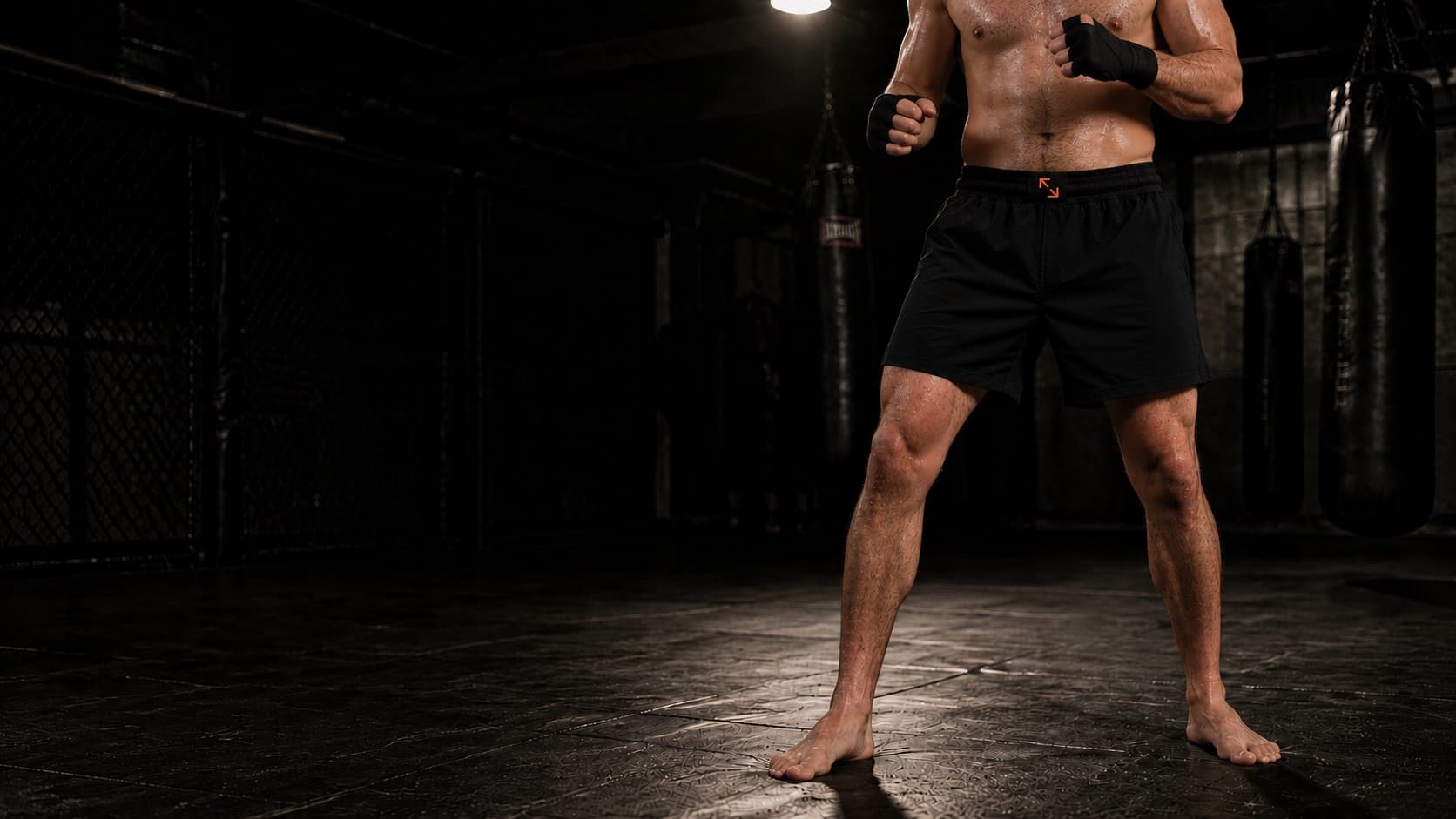 Athlete training in a dark gym wearing Fight Form natural fiber organic cotton shorts for combat sports.
